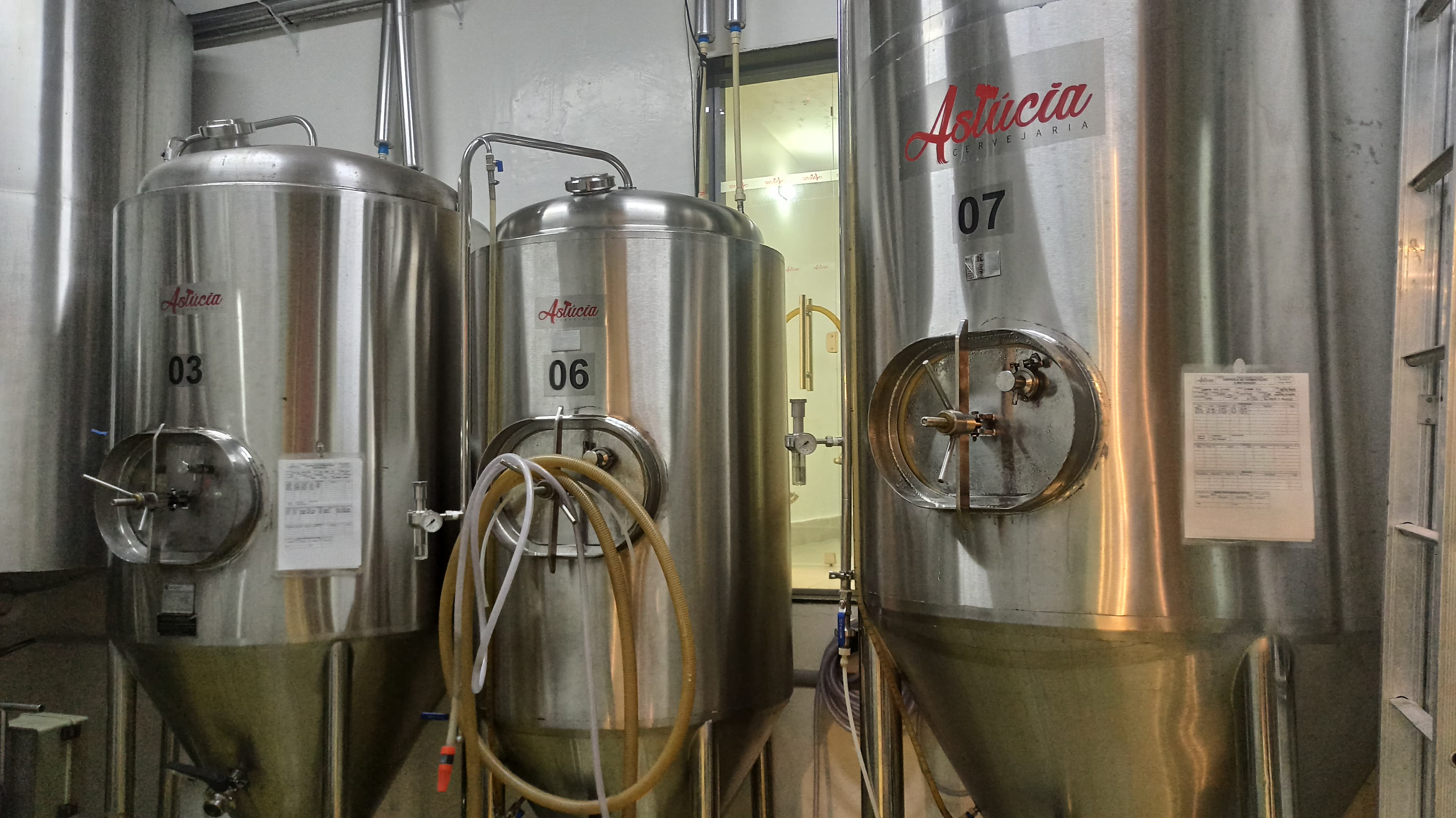 Tanques de fermentação em aço inox com o logo da Cervejaria Astúcia