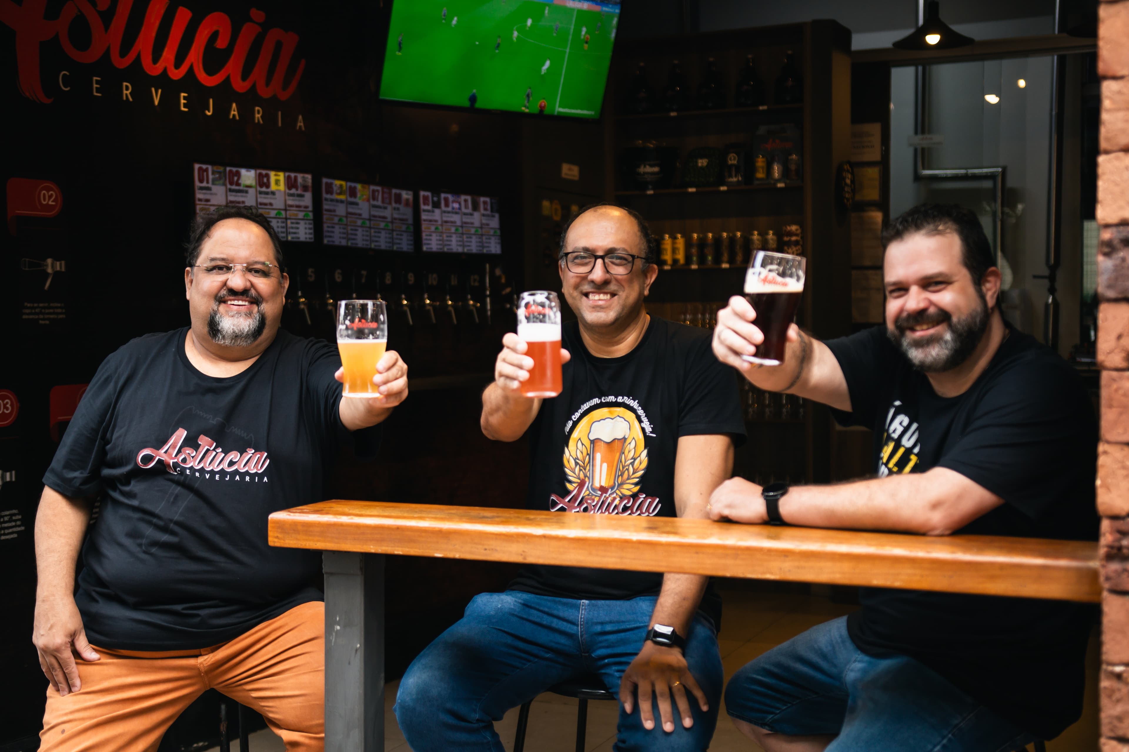 Equipe da Astúcia no balcão do taproom brindando com cervejas
